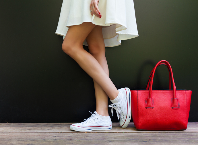 Beautiful fashionable big red handbag standing next to leggy woman