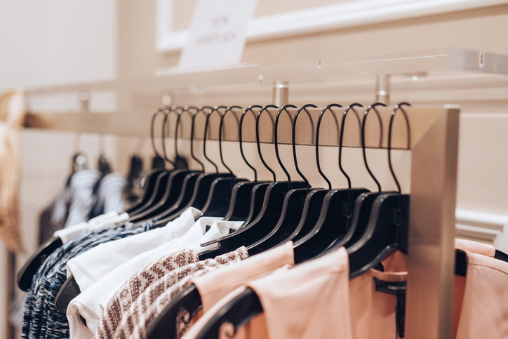 Dresses hanging on a rack in a clothing store.